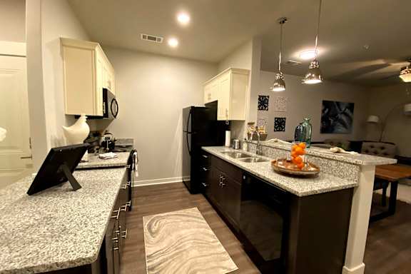 A kitchen with granite countertops and a black refrigerator at McHenry Square Apartments, Georgia