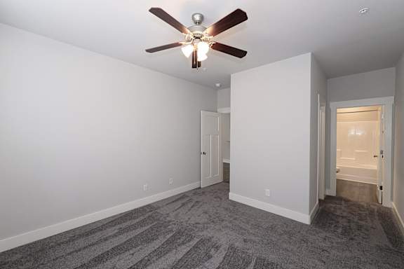 A room with a ceiling fan and carpeted floor at McHenry Square Apartments, Georgia