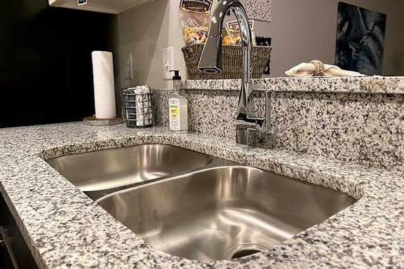 A modern kitchen sink with a granite countertop and a chrome faucet at McHenry Square Apartments, Georgia, 30909