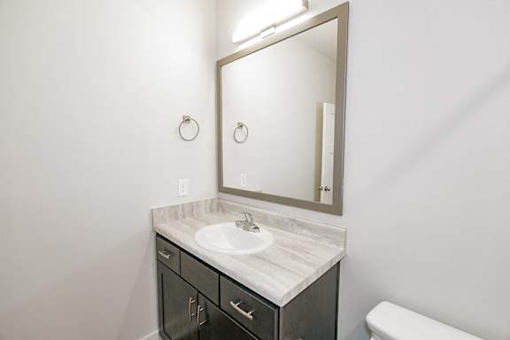 A bathroom with a sink, mirror, and toilet at McHenry Square Apartments, Augusta