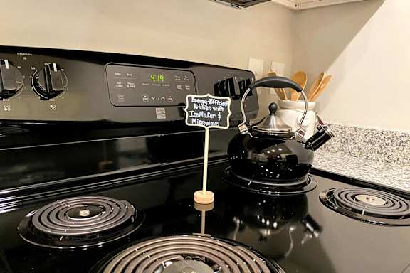 A black stove top with a kettle on it and a sign at McHenry Square Apartments, Augusta, GA