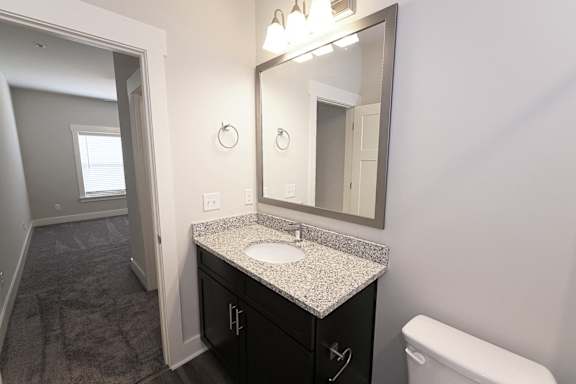 A bathroom with a sink, mirror, and toilet at McHenry Square Apartments, Augusta, GA