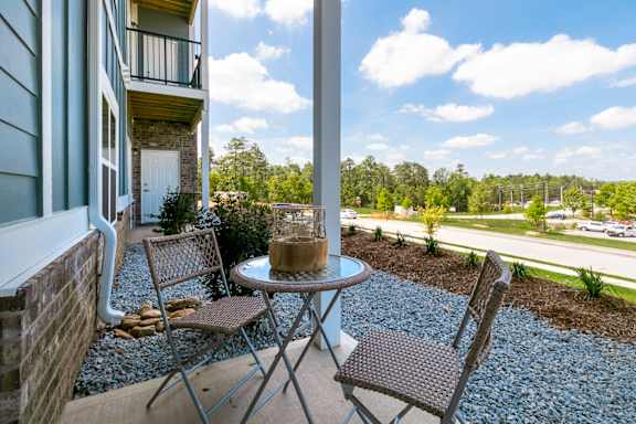 A patio with a table and chairs overlooking a parking lot at McHenry Square Apartments, Augusta, GA
