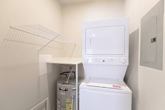 A white dryer is in a small, white-walled laundry room. at McHenry Square Apartments, Georgia