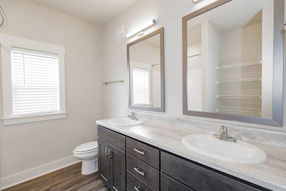 A bathroom with a toilet, sink, and mirror at McHenry Square Apartments, Augusta, Georgia