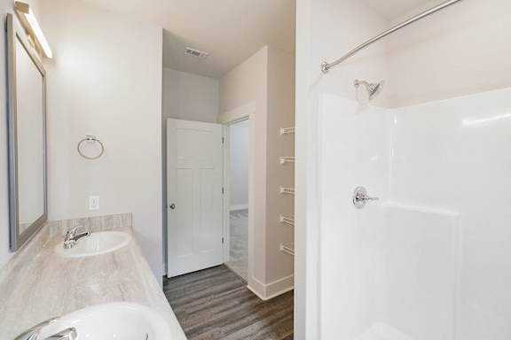 A bathroom with a sink, mirror, and bathtub at McHenry Square Apartments, Augusta