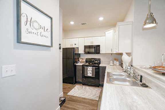 A kitchen with a fridge, oven, and sink at McHenry Square Apartments, Augusta, GA