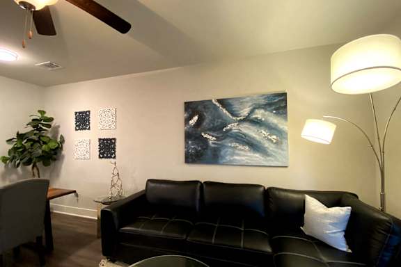 A living room with a black couch and a ceiling fan at McHenry Square Apartments, Augusta, GA