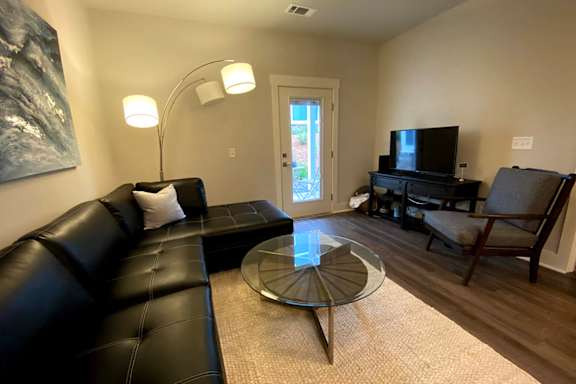 A black leather couch sits in a living room with a glass coffee table in front of it at McHenry Square Apartments, Augusta, Georgia