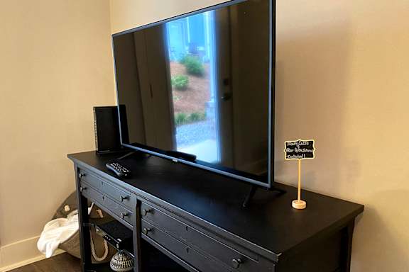 A black television sits on a black dresser with a remote control and speaker in front of it at McHenry Square Apartments, Augusta