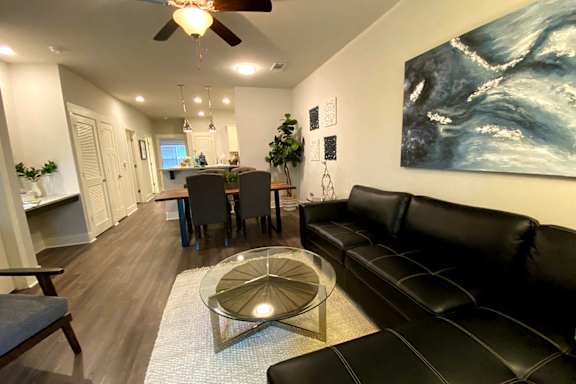 A living room with a black leather couch and a glass coffee table at McHenry Square Apartments, Georgia, 30909