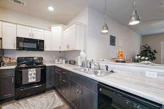A modern kitchen with dark wood cabinets and a black stove top oven at McHenry Square Apartments, Augusta, Georgia