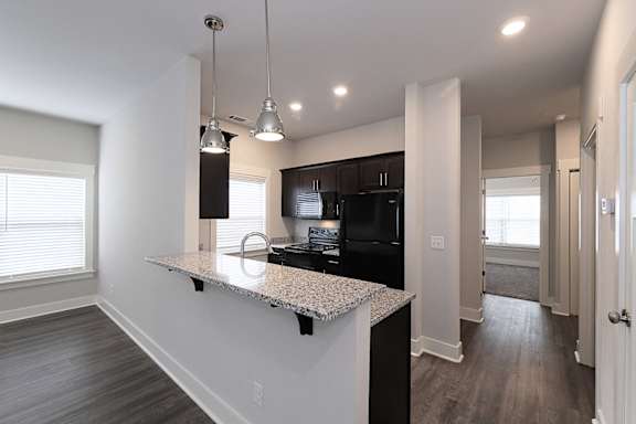 A kitchen with a granite countertop and black cabinets at McHenry Square Apartments, Georgia, 30909