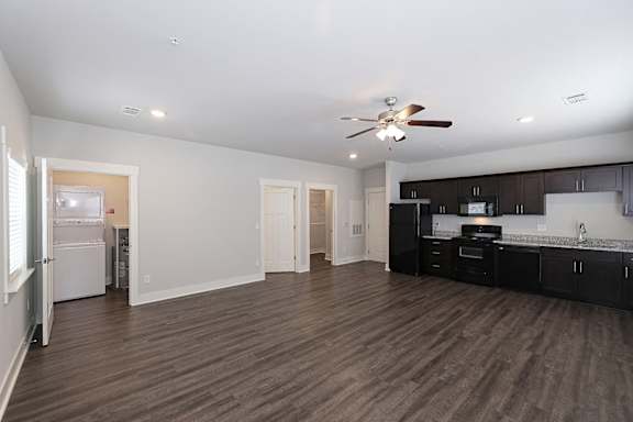 A spacious kitchen and living room with wood flooring and modern appliances at McHenry Square Apartments, Georgia