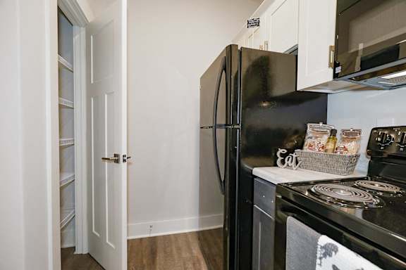 A black fridge in a kitchen with a white door at McHenry Square Apartments, Georgia