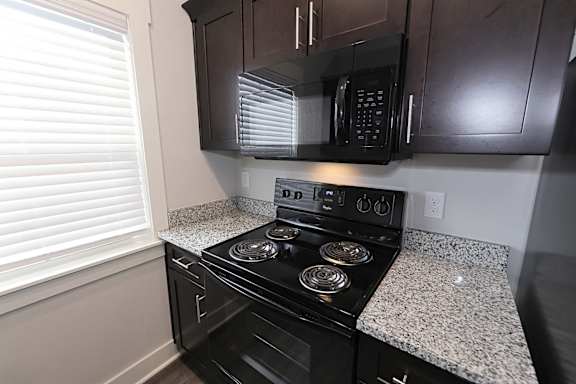 A black stove top oven with a microwave above it at McHenry Square Apartments, Augusta, GA