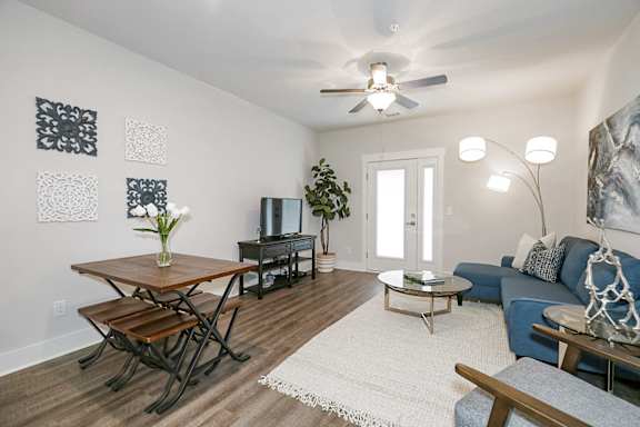 A living room with a blue couch and a wooden dining table at McHenry Square Apartments, Georgia, 30909