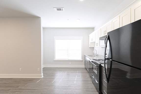 A kitchen with a black refrigerator and wooden floors. at McHenry Square Apartments, Augusta, Georgia