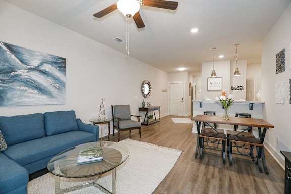 A living room with a blue couch and a glass coffee table at McHenry Square Apartments, Georgia, 30909