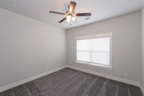 A room with a ceiling fan and a window with blinds at McHenry Square Apartments, Augusta, Georgia