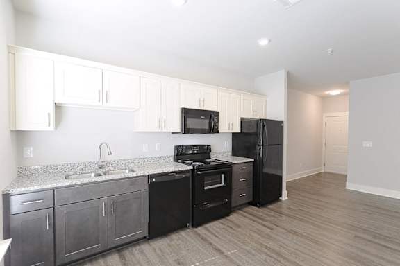 A kitchen with black appliances and wooden floors at McHenry Square Apartments, Augusta