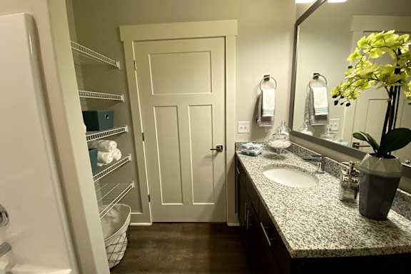 A bathroom with a white door, a sink, and a mirror at McHenry Square Apartments, Augusta, Georgia