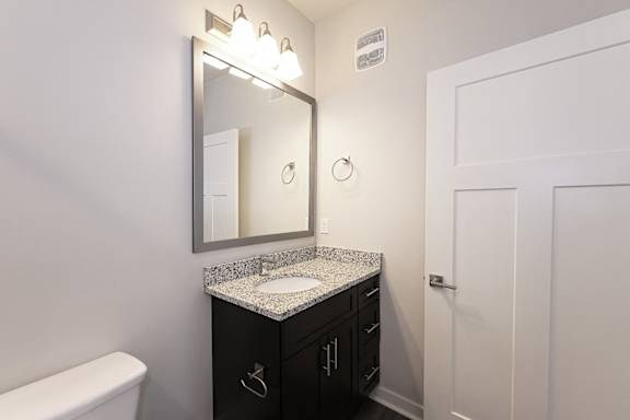 A bathroom with a white tub, sink, and mirror at McHenry Square Apartments, Augusta, GA