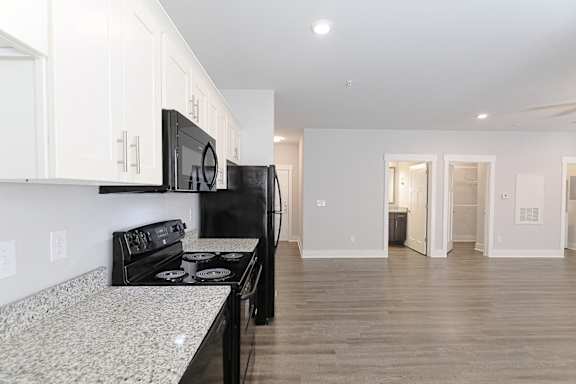 A kitchen with black appliances and white cabinets. at McHenry Square Apartments, Georgia