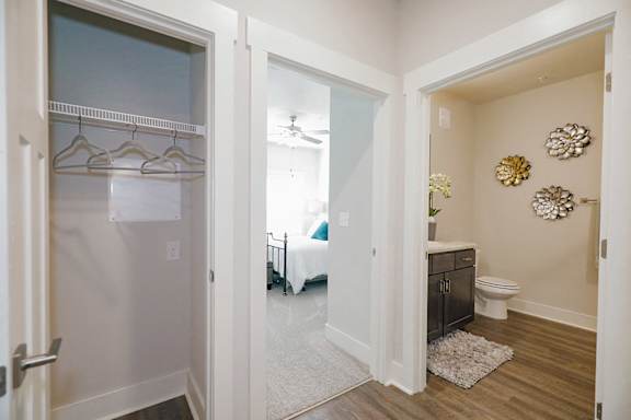 A white hallway with a bedroom and bathroom visible through the open door at McHenry Square Apartments, Augusta, GA