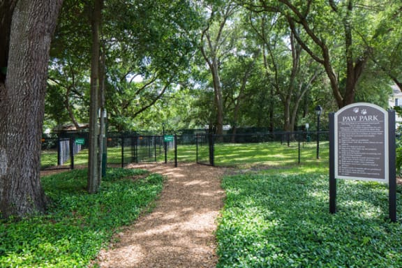 Fenced dog park entrance with shaded walking path at The Arbor Walk Apartments, Tampa, FL 33617