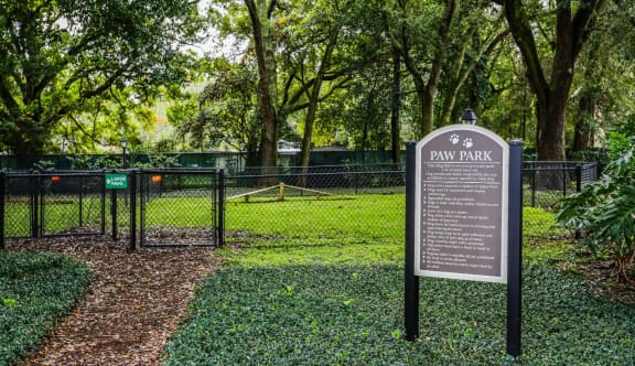 Fenced dog park with rules signage and grassy play area at The Arbor Walk Apartments, Tampa, Florida
