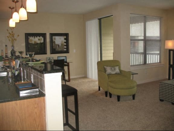 A living room with a green chair and a black and white checkered ottoman at West Inman Lofts Apartments, Atlanta