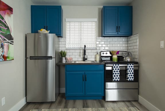 Kitchen in 1 bedroom apartment at Fusion Las Vegas with efficient, stainless-steel appliances and dark blue cabinets.