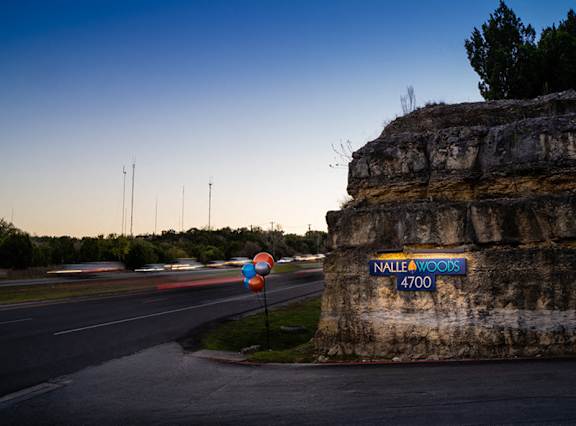 Property entrance sign illuminated at dusk at Nalle Woods of Westlake Apartments, Texas, 78746
