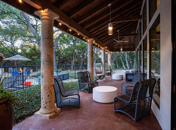 Covered outdoor lounge with hanging chairs and pool views at Nalle Woods of Westlake Apartments, Austin, TX