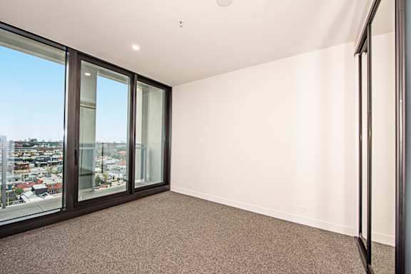 A room with a carpet floor and a window overlooking a city.