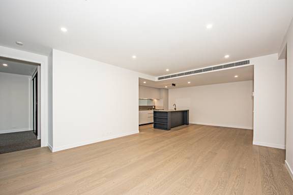 A spacious room with a black desk and wooden flooring.