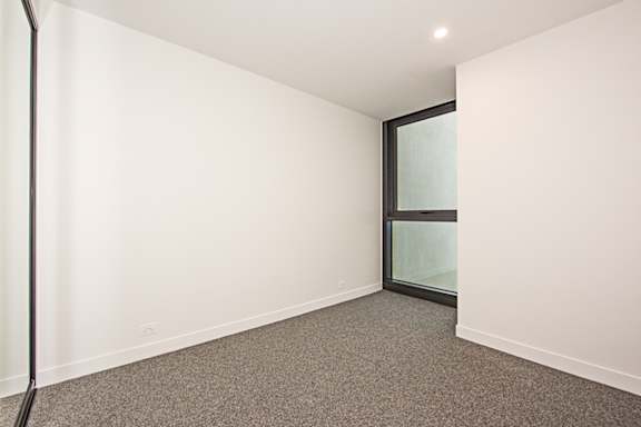 A room with a grey carpet and a glass door.