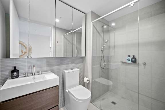 A modern bathroom with a white toilet and a walk-in shower.