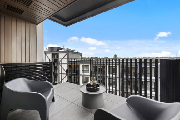 two chairs and a table on a balcony overlooking the city