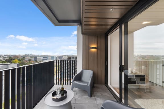 a balcony with two chairs and a table and a view of the city