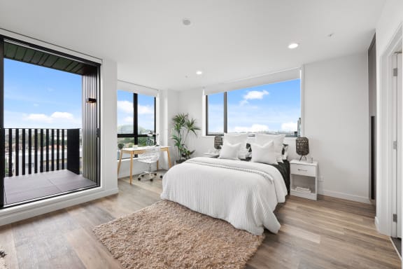 a white bedroom with a large bed and a balcony