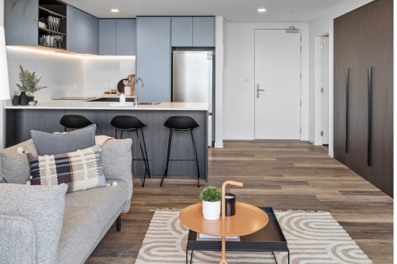 a living room with a couch and a kitchen with stools