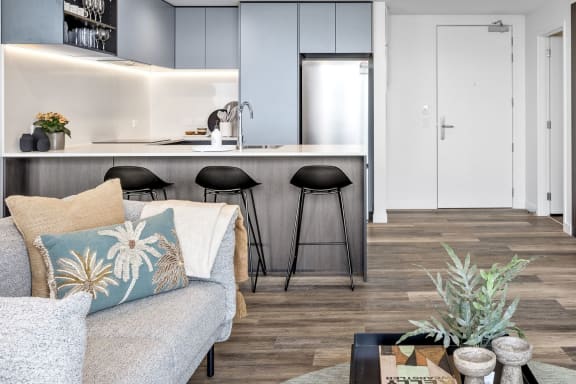 a living area with a couch and a kitchen with bar stools