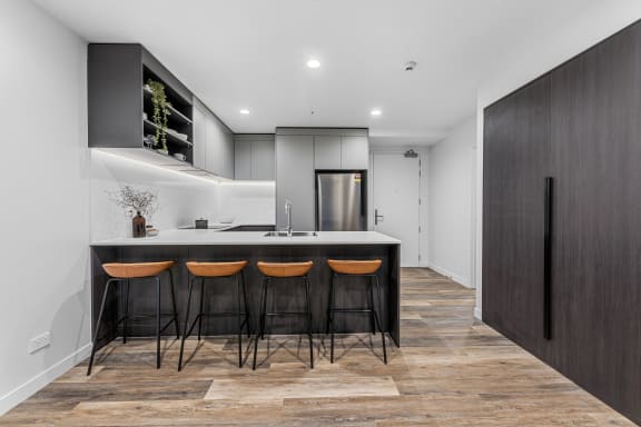 a kitchen with a black counter top and three stools