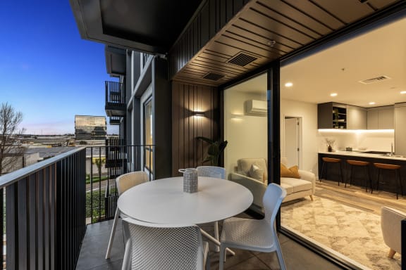 a dining area with a white table and chairs on a balcony