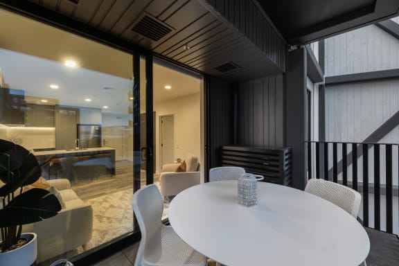 a dining area with a white table and chairs and a kitchen in the background