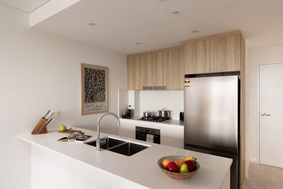 A modern kitchen with a white countertop and stainless steel appliances.