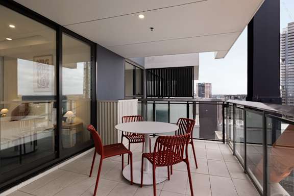 A balcony with a table and chairs overlooking a cityscape.
