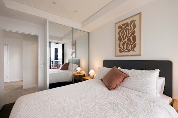 A bedroom with a large bed and a mirror on the wall.